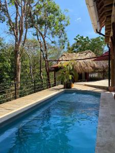 ein Pool neben einem Haus mit Strohdach in der Unterkunft Its a Lifestyle Rancho Room in San Juan del Sur