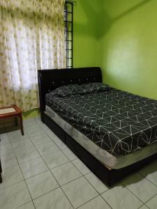 a bed in a room with a green wall at Guest house sri purnama banggol in Kota Bharu