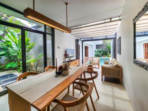 ein Esszimmer mit einem großen Holztisch und Stühlen in der Unterkunft Silk Umalas by Nagisa Bali in Kerobokan
