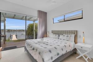 a bedroom with a bed with a view of the water at Lake Front - Outdoor Hot tub in Merimbula