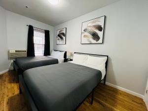 2 letti in una camera con pareti bianche e pavimenti in legno di The Upper West Side a New York