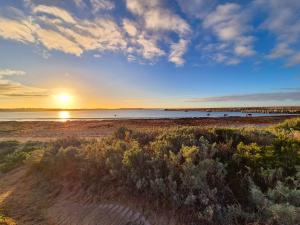 una playa con puesta de sol sobre el agua en Four bedroom beachside apartment, en Warrnambool