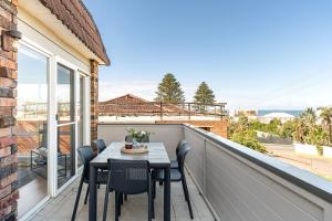 a patio with a table and chairs on a balcony at 200m to the beach Pet friendly in Wamberal
