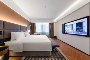 海口市にあるIntercity Hotel Haikou High Speed Rail East Stationのベッドと薄型テレビがあるホテルの部屋