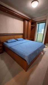 a bedroom with a bed with blue sheets and a window at apartement cempaka mas in Jakarta