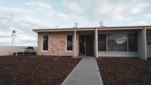 a house with a lighthouse in the background at Point Lowly Cottages in Whyalla