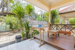 Funny Homestay 2 في غيلي تراوانغان: شرفة خشبية مع مقعد وطاولة