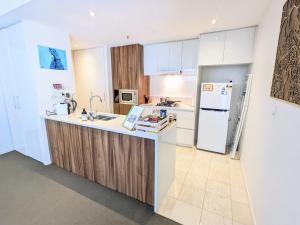 The Loft 3BDR, City Centre, Family-Friendly, King Bed, Massage Chair, Parking في كانبرا: مطبخ بخزائن بيضاء وثلاجة بيضاء