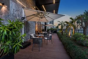 海口市にあるIntercity Hotel Haikou High Speed Rail East Stationのパティオ(テーブル、椅子、パラソル付)