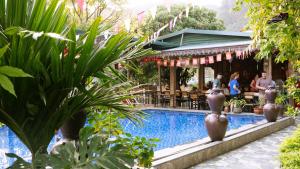 a pool at a resort with people sitting at tables at Tam Coc River View Homestay in Ninh Binh