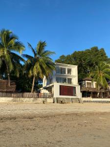 a white house on the beach with palm trees at Villalola in Nosy Be