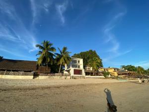 a person standing on a beach with a house in the background at Villalola in Nosy Be +10 photos