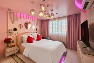 Habitación de color rosa con cama y TV en Secret Garden Hotel Ben Thanh, en Ho Chi Minh