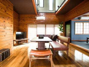 een eetkamer met een tafel, stoelen en een tv bij Little Hermit by SANA in Tateyama