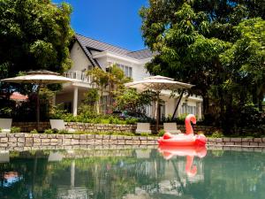 a red swan in a pool in front of a house at Hoa Lan Garden Hồ Tràm in Ho Tram