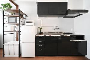 a kitchen with black cabinets and a white refrigerator at Cocoro404 in Kichijōji