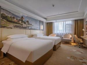a hotel room with three beds and a desk at Vienna Hotel Yunnan Lijiang Ancient City in Lijiang