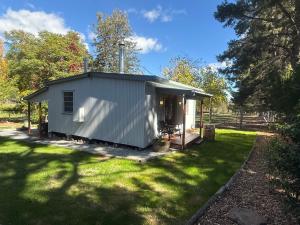 ein kleiner weißer Schuppen in einem Hof mit Gras in der Unterkunft Martali Cottage in Wyberba