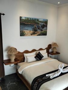 a bedroom with a bed with a painting on the wall at Ijen Cottages in Jambu +12 photos