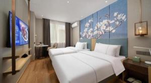 a bedroom with a large white bed and a tv at Magnotel Changsha Wuyi Square Metro Station National Finacial Center in Changsha