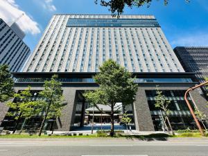 a tall building with a tree in front of it at Tokyu Vacations Osaka Midosuji in Osaka
