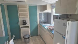 Il comprend une cuisine dotée d'un réfrigérateur blanc et de murs bleus. dans l'établissement Magnifique Mobilhome au camping le Chateau de Galaure, à Châteauneuf-de-Galaure