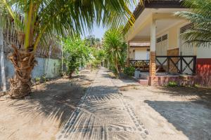 Funny Homestay 2 في غيلي تراوانغان: طريق ترابي به أشجار نخيل بجوار منزل