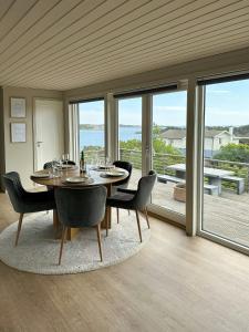 ein Esszimmer mit Tisch und Stühlen und Fenstern in der Unterkunft Cabin With Views And A Large Terrace In Søgne in Søgne