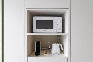 un horno microondas blanco sentado en la parte superior de un estante en Urbanstay Myeongdong, en Seúl 37 fotos más