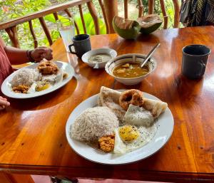 a wooden table with plates of food on it at Prime Surfers Bungalow in Arugam Bay