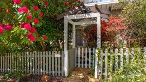 Una valla blanca con una puerta y flores rosas. en Crabapple Southside Mountain Cottage Pet Friendly, en Wentworth Falls