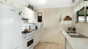 Una cocina blanca con estufa y fregadero. en Blue Mountains National Park Valley Views, en Wentworth Falls