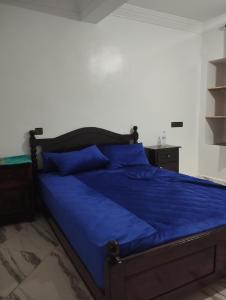 a blue bed with blue pillows in a bedroom at L'airoport in Oulad Tayeb