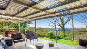 a patio with chairs and a table and a large window at Hat Hill Hideaway Amazing Valley Views in Blackheath
