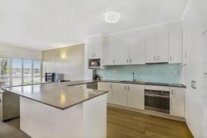 a kitchen with white cabinets and a counter top at Noosa River Gardens in Noosaville +7 photos