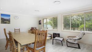 a dining room with a table and chairs and windows at Refresham Katoomba South in Katoomba