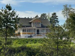 a large house with a porch and trees at Anolanranta Beach House - Golf & Lake in Pieksamaki