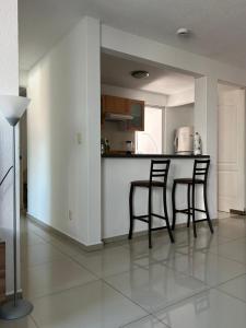 a kitchen with two bar stools and a counter at Cómodo Departamento en San Andrés Cholula in Cholula