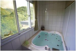 六龜區的住宿－松柏林民宿渡假山莊，带浴缸的浴室和窗户。
