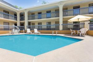 a pool in front of a hotel with chairs and umbrellas at Days Inn by Wyndham Elberton in Elberton