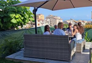 a group of people sitting at a table under an umbrella at Atlantide Suites Tropea in Tropea