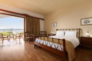 A bed or beds in a room at Ramada Loutraki Poseidon Resort