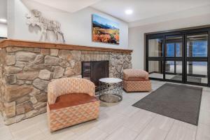 a living room with a stone fireplace and two chairs at Microtel Inn & Suites by Wyndham Georgetown Lake in Georgetown +26 photos