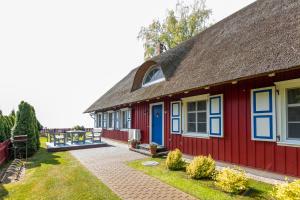 ein rotes Haus mit Reetdach und Terrasse in der Unterkunft Vila Pervalka in Pervalka