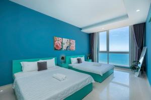 two beds in a room with a blue wall at Oasky Vũng Tàu - Pooh House 5 in Vung Tau +60 photos