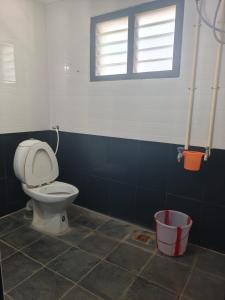 a bathroom with a toilet and a bucket at Mahanas Paradise in Thanjāvūr +5 photos