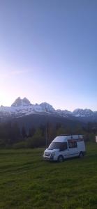 a van parked in a field with mountains in the background at Ford Transit Motorhome-Camper in Batumi