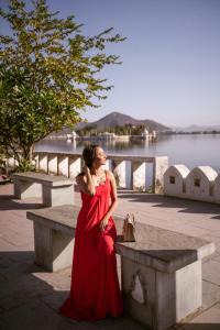 a woman in a red dress sitting on a bench at Panna Vilas - A Lake Facing Boutique Hotel in Udaipur