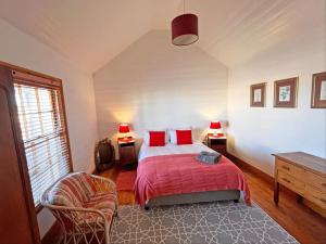 a bedroom with a bed and a chair and two lamps at Grazia Cottages in Port Nolloth