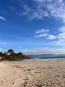 a sandy beach with a blue sky and the ocean at A Loureira in Portonovo